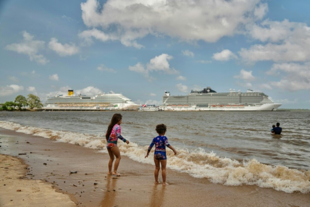 Children bathe on a beach along the Guamá River with cruise ships seen in the background docked at the Port of Outeiro