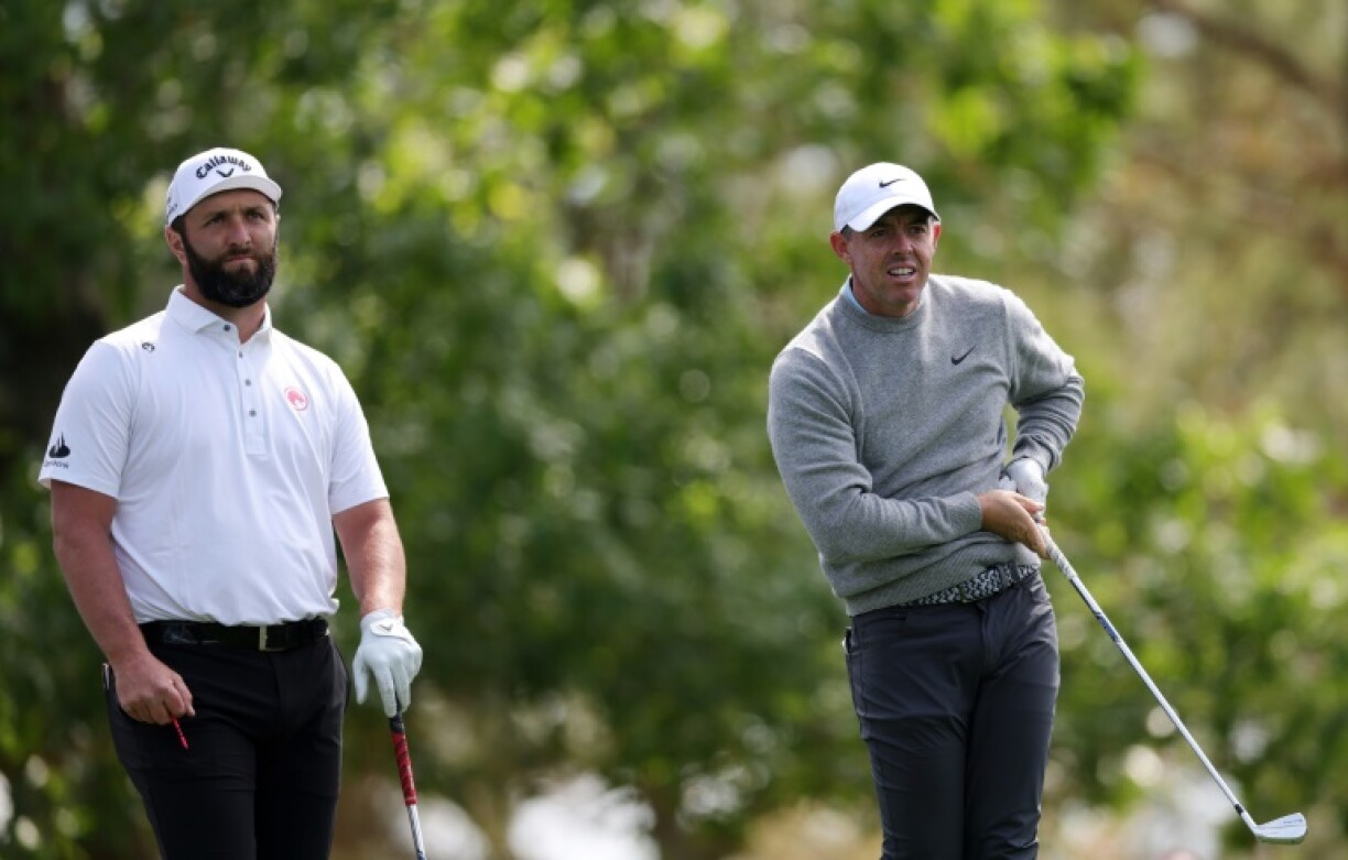Jon Rahm of Spain looks on as Rory McIlroy of Northern Ireland plays a shot during a practice round before the Masters at Augusta National