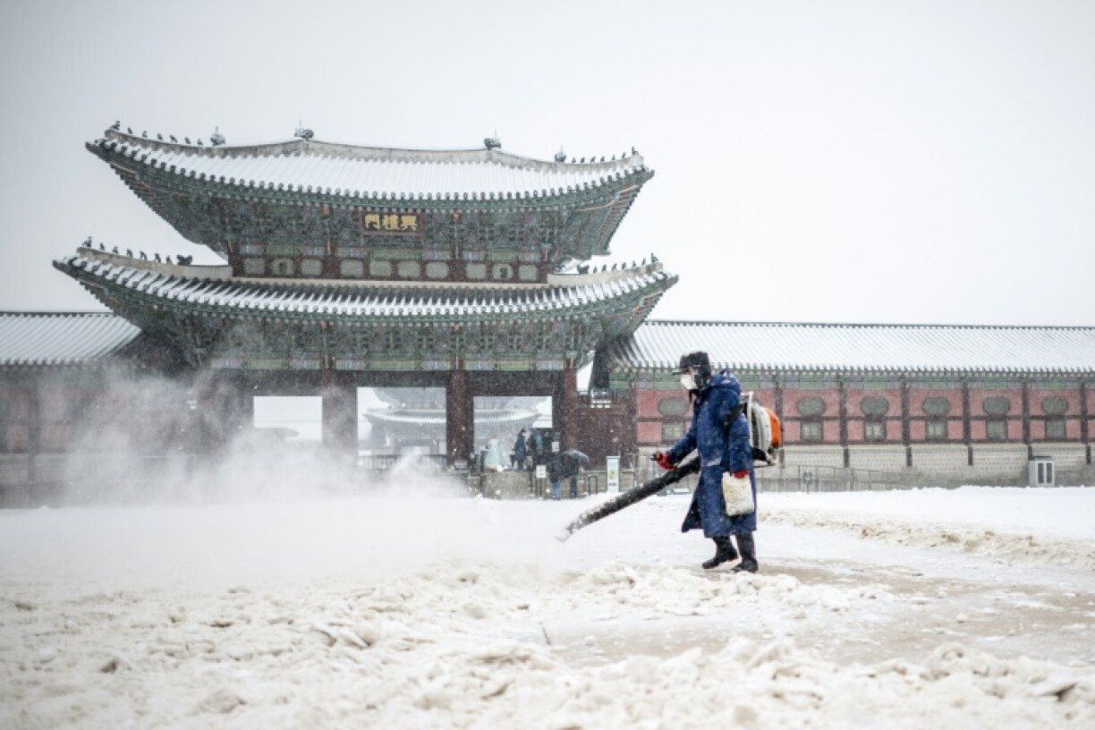 A staff member works at the Gwanghwamun gate during snowfall in Seoul