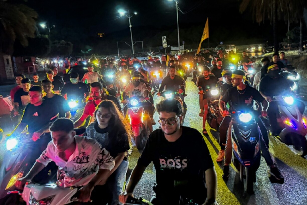 Supporters of Lebanon's Hezbollah militant group lift flags as they rally in cars and motorbikes in Beiruit to protest the government's endorsement of a plan to disarm it