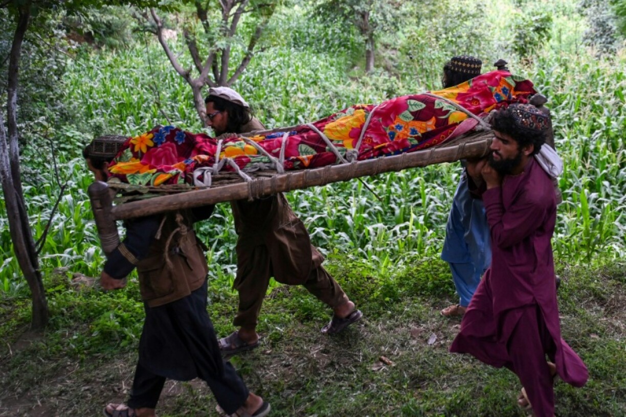 Afghan men carry the shrouded body of an earthquake victim for burial in Nurgal, Junar province
