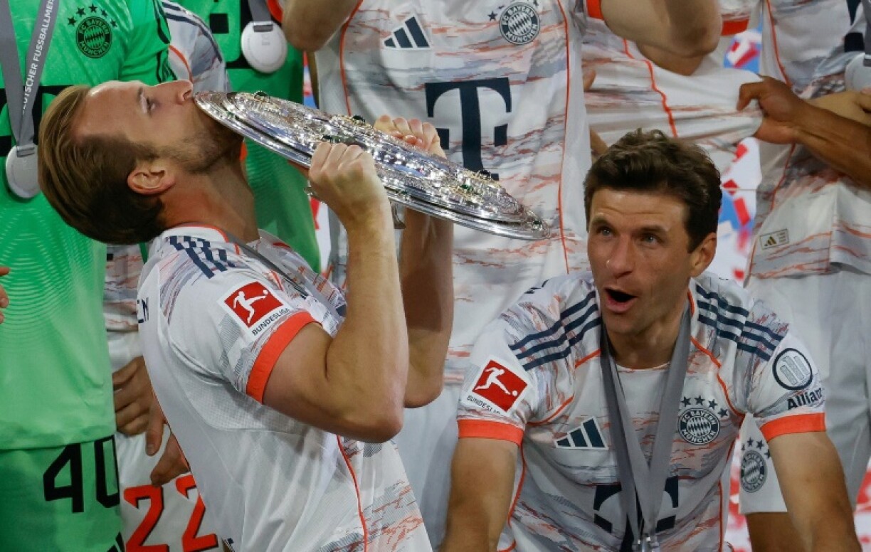 Harry Kane kisses the Bundesliga shield as his Bayern Munich teammate Thomas Mueller looks on.