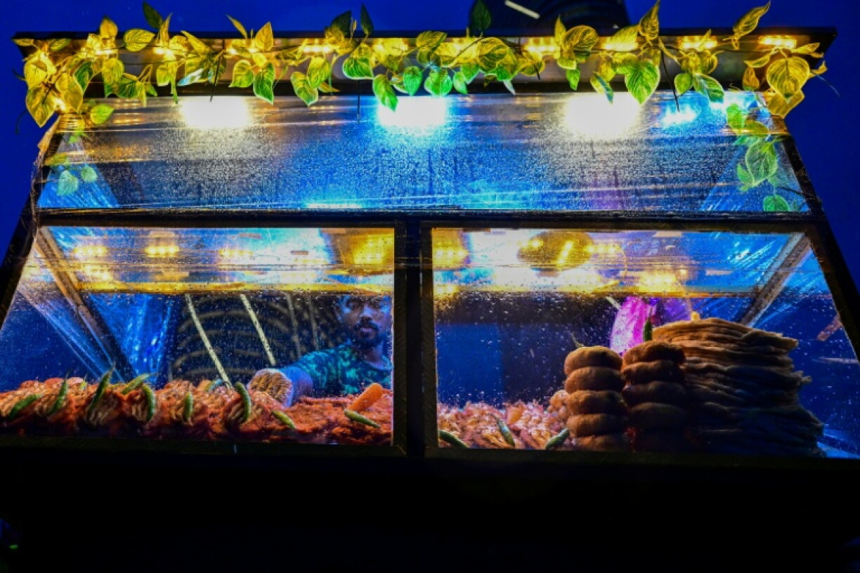 A vendor selling prawns waits for customers at the Galle Face seafront promenade as it rains in Colombo on October 26. The country has ordered some schools shut with the approach of Cyclone Arnab