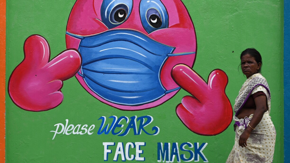 A woman walks past a Covid-19 coronavirus awareness mural along the roadside in Chennai on September 13, 2021.