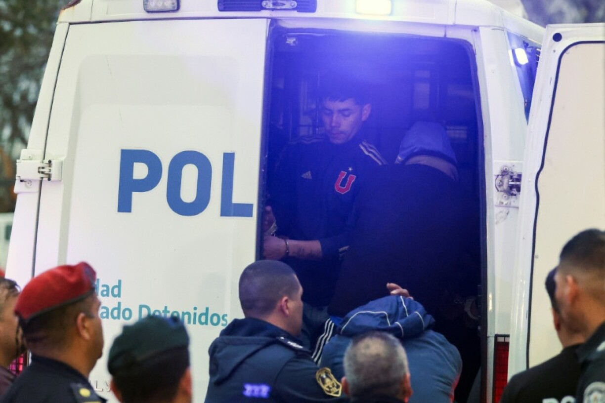 Universidad de Chile fans are loaded into a police van after an outbreak of football violence at Argentine Independiente's stadium