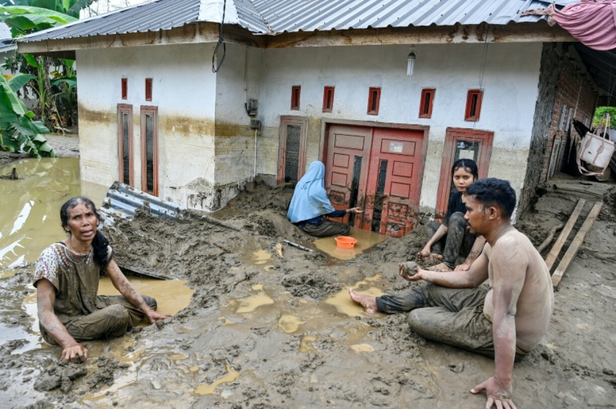 Des habitants dégagent une épaisse couche de boue à l’entrée d’une maison inondée à la suite de crues soudaines à Meureudu, dans la province d’Aceh, en Indonésie, le 28 novembre 2025