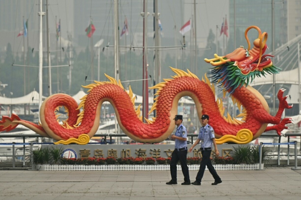 Police officers walk past a dragon sculpture as they patrol the venue hosting the Defence Ministers' Meeting of the Shanghai Cooperation Organization (SCO) Member States in Qingdao, in eastern China's Shandong province on June 26, 2025.