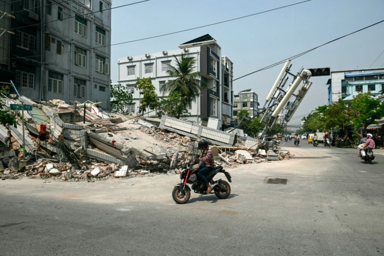 A man rides his motorbike past a collapsed building in Mandalay on April 2, 2025