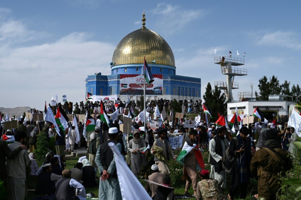 Afghan men holding Taliban flags and Palestinian national flags take part in an anti-Israel protest to show their solidarity with Palestinians after the Friday prayers