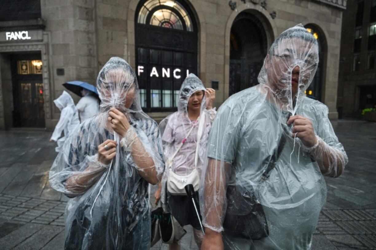People protect themselves with disposable rain ponchos as Typhoon Co-May hits Shanghai
