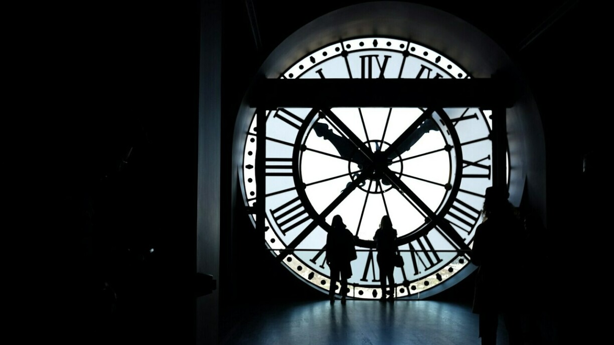 Des femmes regardent la Seine à travers l'horloge géante du musée d'Orsay à Paris