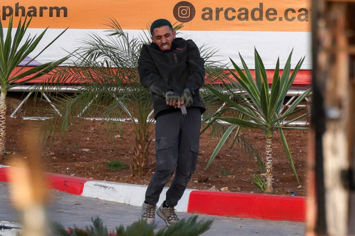 One of two armed Palestinian men loads his firearm during a fire exchange with Israeli forces at the northern checkpoint of Hebron in the Israeli-occupied West Bank on