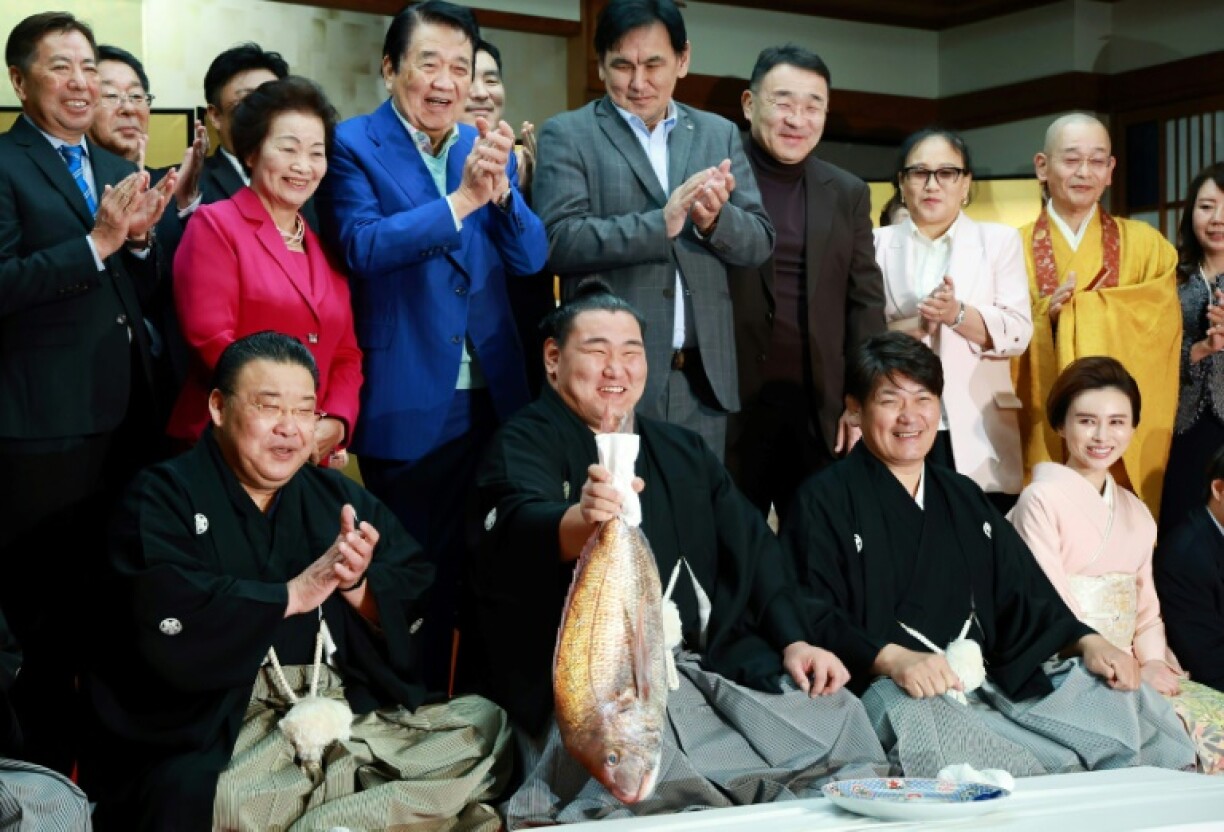 Sumo wrestler Hoshoryu holds a fish to celebrate being promoted to the sport's highest rank of yokozuna