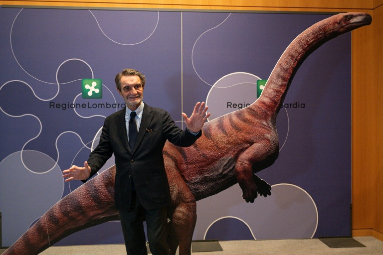 Attilio Fontana, président de la région italienne de Lombardie, pose pour une photo avec un dinosaure en carton lors d'une conférence de presse pour présenter la découverte de milliers d'empreintes de dinosaures dans le parc national du Stelvio, en Italie, près des zones qui accueilleront les Jeux olympiques d'hiver e Milan-Cortina 2026, à Milan, le 16 décembre 2025. On estime que ces empreintes appartiennent à des dinosaures prosauropodes du Trias supérieur, datant de 210 millions d'années.