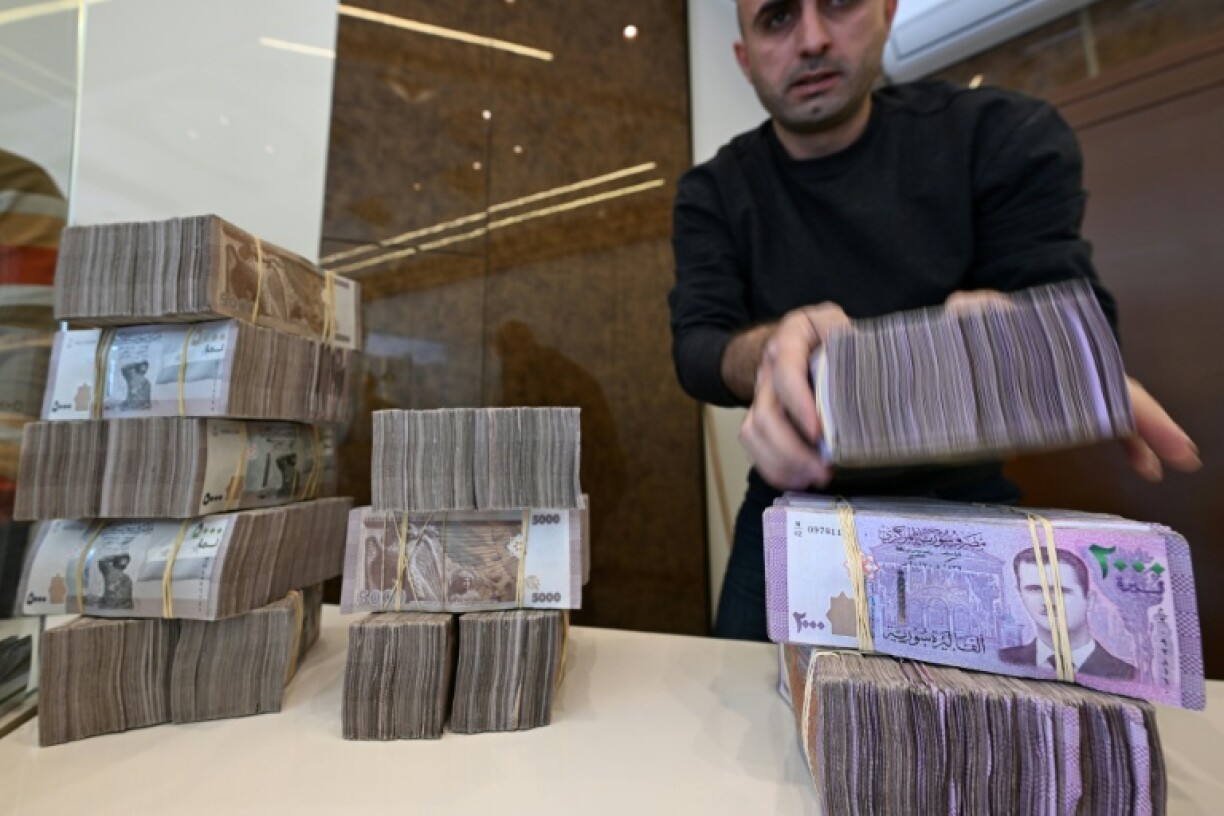 An employee stacks Syrian bills at a Damascus currency exchange -- a trade outlawed under former president Bashar al-Assad