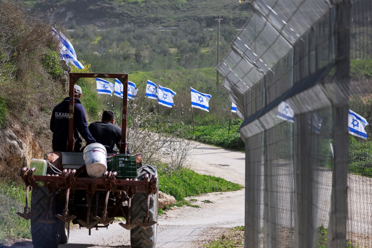 E paläestinensesche Bauer fiert mat sengem Trakter laanscht eng Strooss, wou Israeelien fändelen ubruecht hunn.