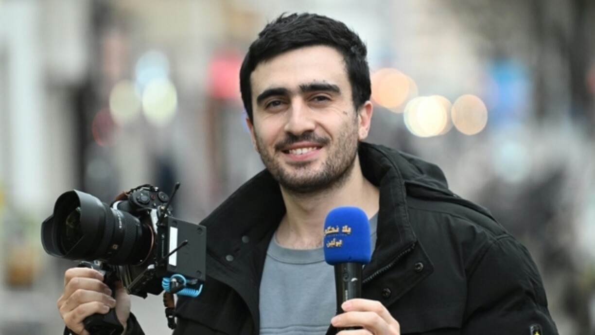 Le journaliste syrien, Anas Modaman, titulaire aujourd'hui d'un passeport allemand, tient un appareil photo et un microphone dans une rue de Berlin, le 11 décembre 2024