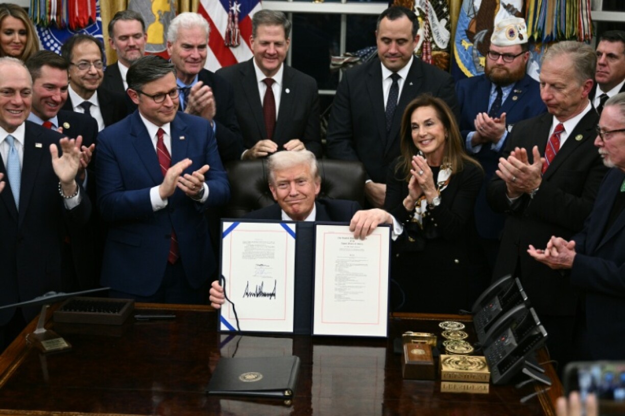 US President Donald Trump (C) shows the signed bill to re-open the federal government in the Oval Office of the White House