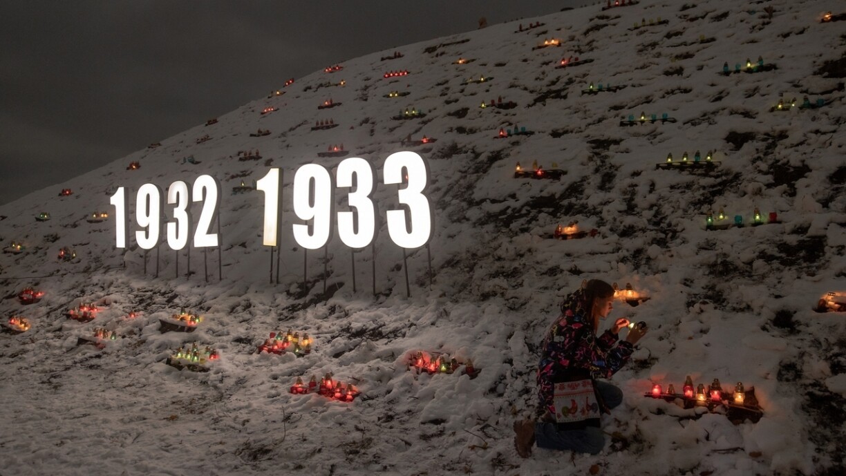 A woman lights a candle in memory of the victims of the 1932–1933 famine in front of the Holodomor monument in Kyiv.