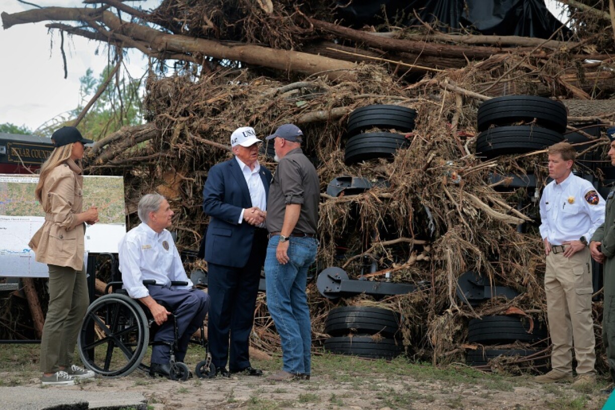 US President Donald Trump, First Lady Melania Trump and Texas Governor Greg Abbott meet local emergency services personnel as they survey flood damage along the Guadalupe River on July 11, 2025 in Kerrville, Texas