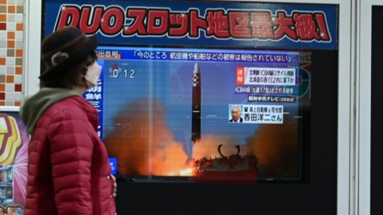 Une passante marche devant un écran de télévision après le tir d'un missile nord-coréen, le 18 novembre 2022 à Tokyo (Japon)