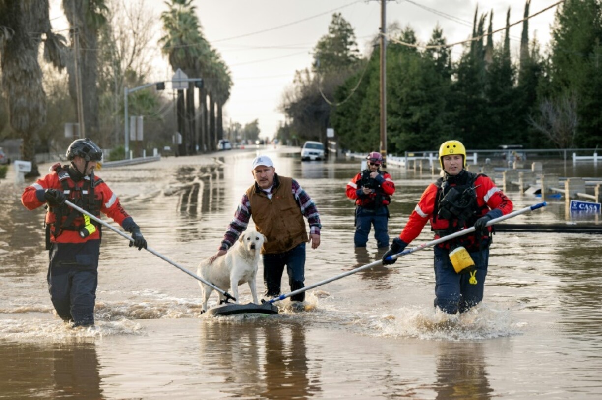 Des pompiers évacuent un homme et son chien, à Merced, en Californie, le 10 janvier 2023