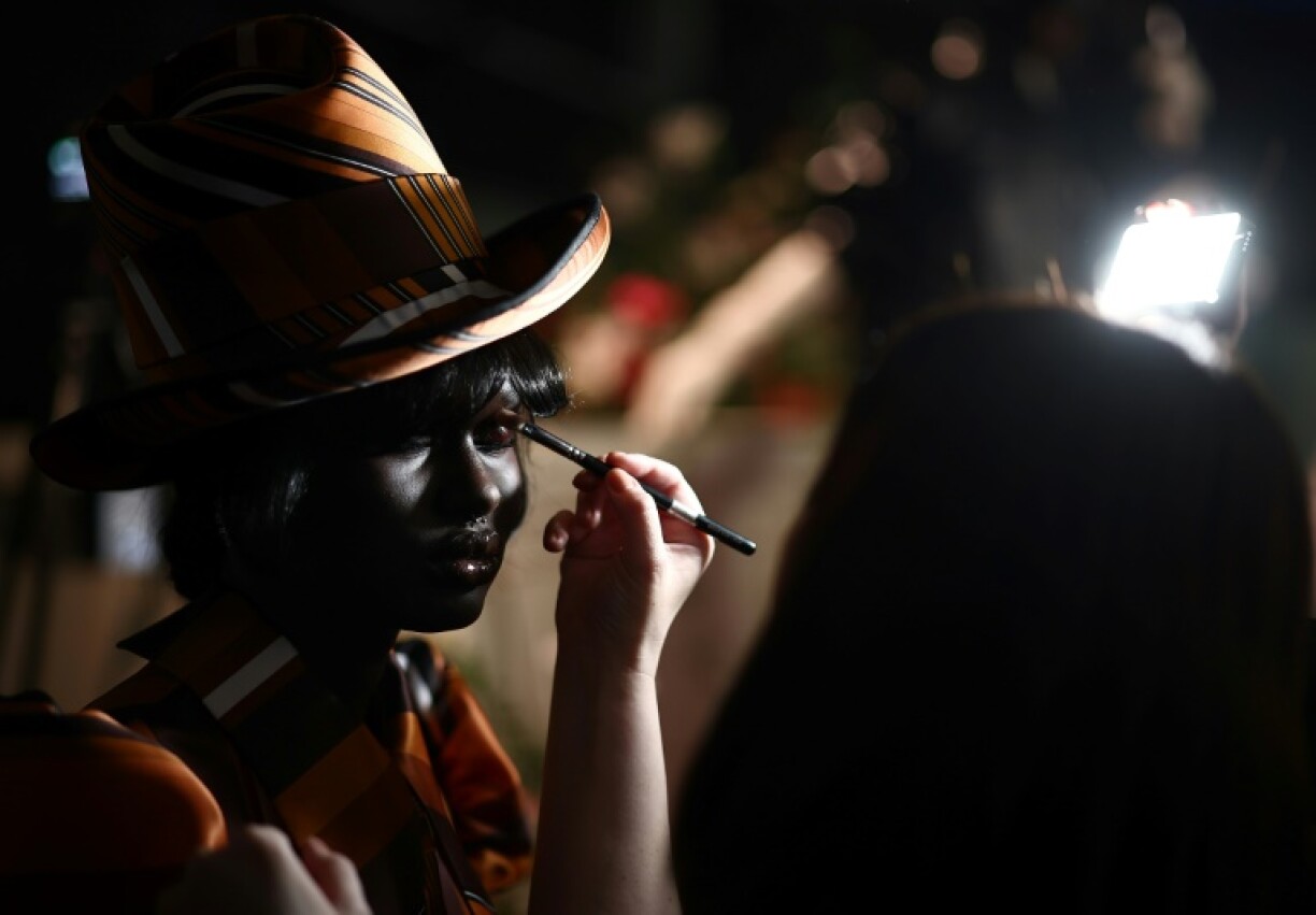 Models have their make up applied before showcasing creations from British-Nigerian designer Tolu Coker