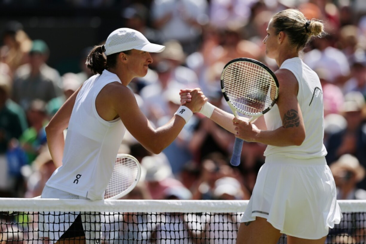 Iga Swiatek (à gauche) et Karolina Pliskova se serrent la main après la victoire de la Polonaise au second tour du tournoi de Wimbledon le 2 juillet 2026 au sud-ouest de Londres