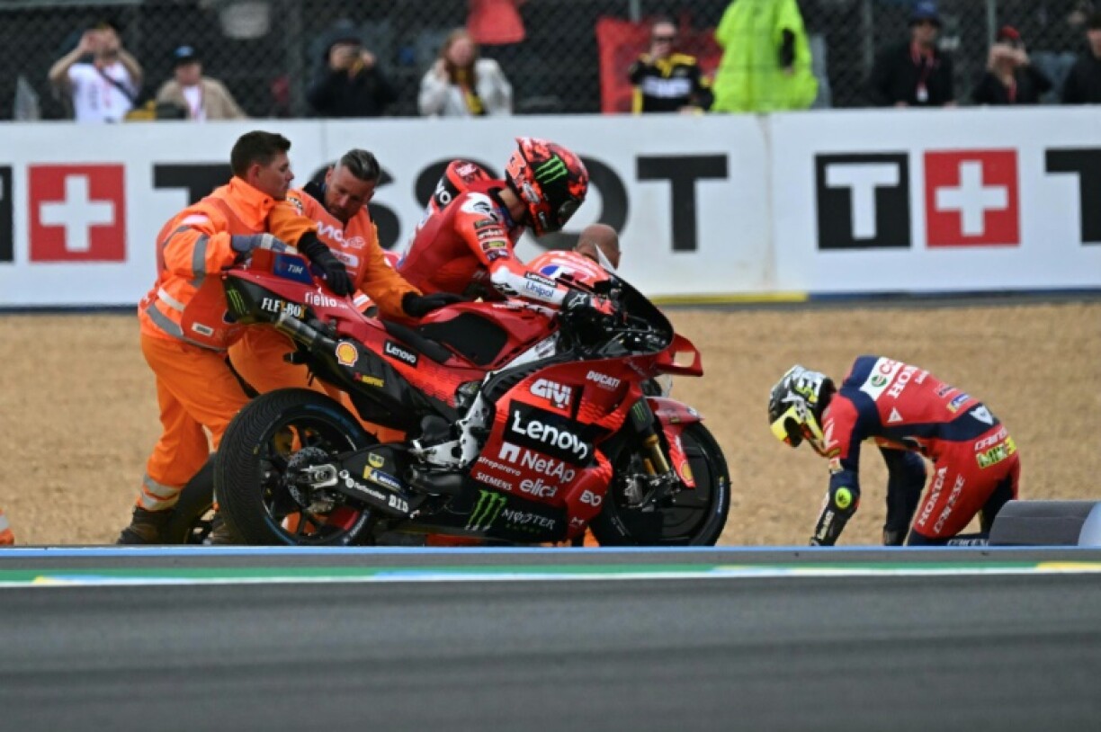 Ducati's Francesco Bagnaia (C) is assisted by track marshals after a crash with Honda's Joan Mir (R) after both came off in the opening lap of the French MotoGP at Le Mans