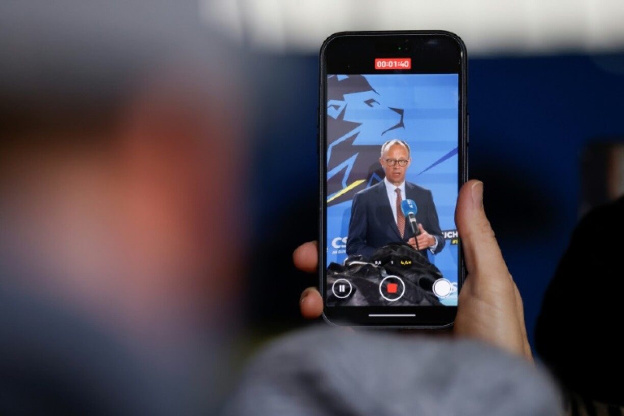 A person holding a mobile phone that shows an address by Friedrich Merz, leader of Germany's Christian Democratic Union