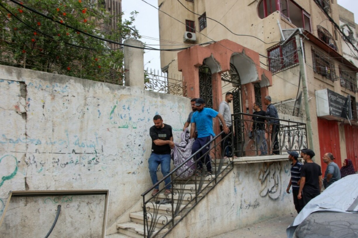Palestinians transport the body of a victim following Israeli strikes which hit apartments in Gaza City's Yarmuk Street