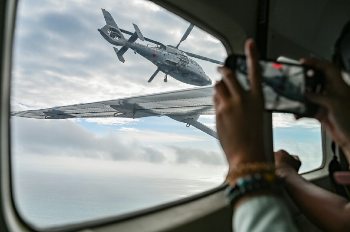 An aircraft identified by the Philippine Coast Guard as a Chinese Navy helicopter (L) flies near a plane carrying journalists over the contested Scarborough Shoal in the South China Sea
