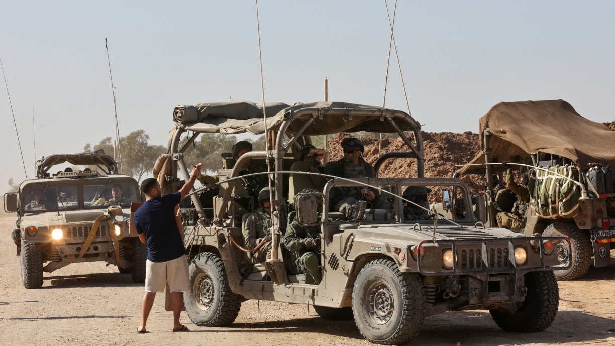A man welcomes Israeli soldiers with snacks upon their arrival in southern Israel after exiting the Gaza Strip through the border fence on November 24, 2023.