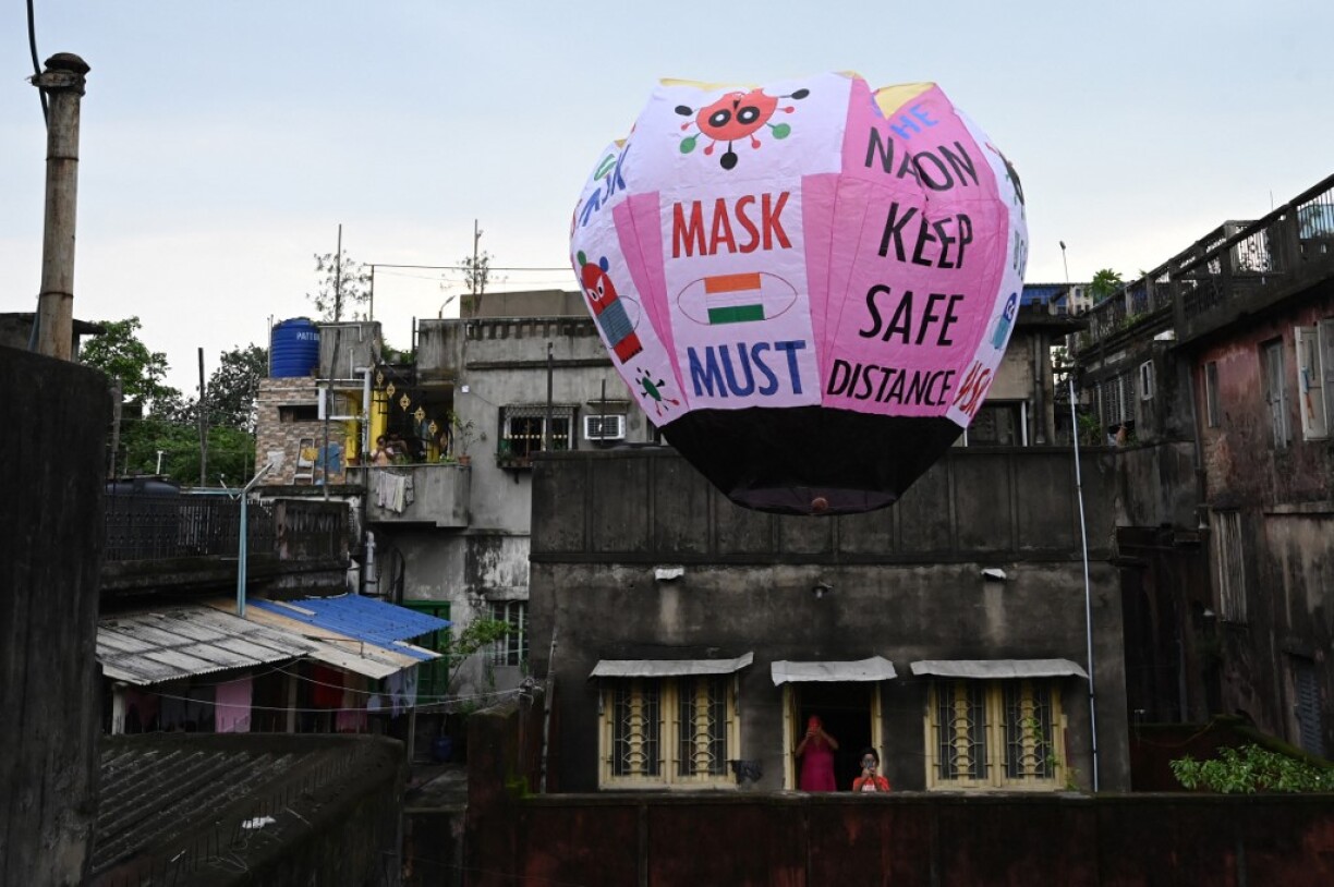 Residents take pictures of a paper lantern released with Covid-19 guidelines to create awareness against the Covid-19 coronavirus in Kolkata on June 22, 2021.
