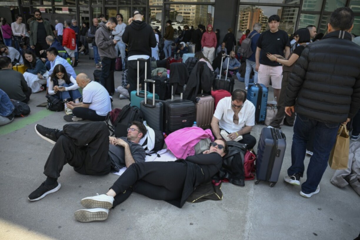 People listen to the radio through the loudspeakers outside Barcelona Sant rail station during a massive power cut