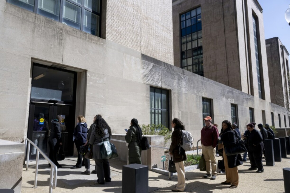 Federal workers wait in line to access to the Mary E. Switzer Memorial Building that houses the US Department of Health and Human Services in Washington, DC