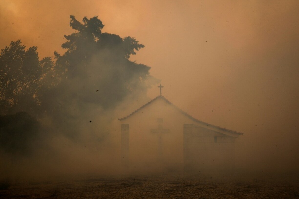 Une chapelle apparait entourée de fumée lors d'un incendie dans le village d'Antas, le 15 août 2025, au Portugal