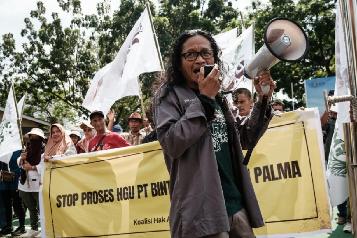 Pralensa, an activist from Lebung Itam, speaking into a megaphone as villagers participate in a rally against plans to convert peatland in their village into a company concession area for plantations