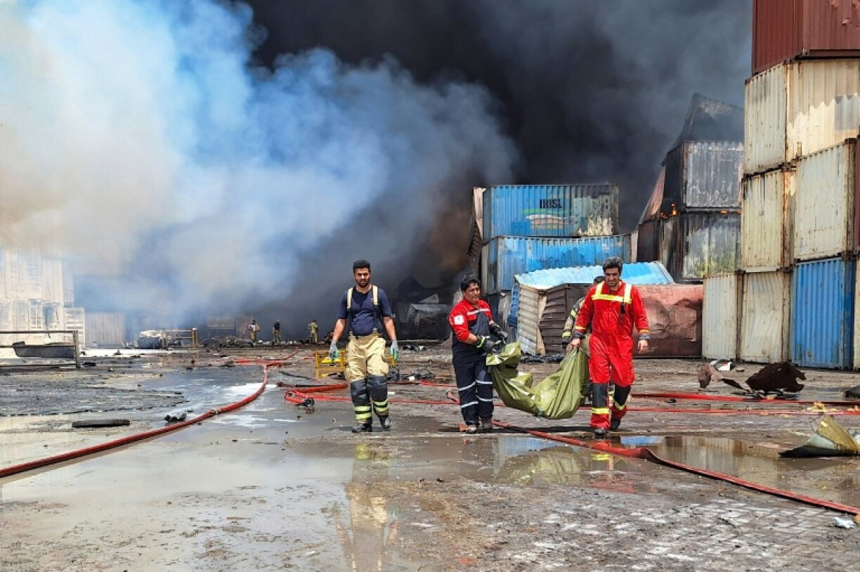 A day after the port blast, Iranian firefighters carry a victim