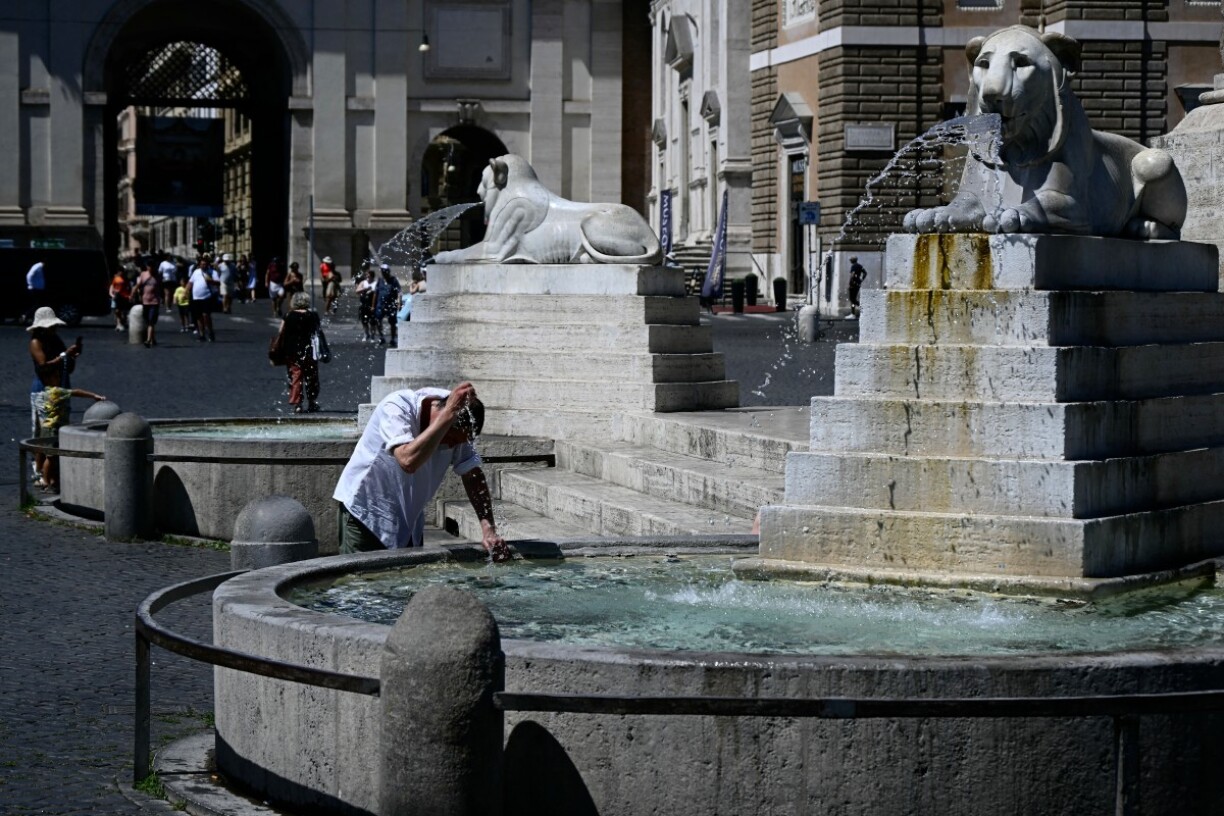 Un touriste se rafraîchit avec l'eau de la fontaine de la Piazza del Popolo à Rome.