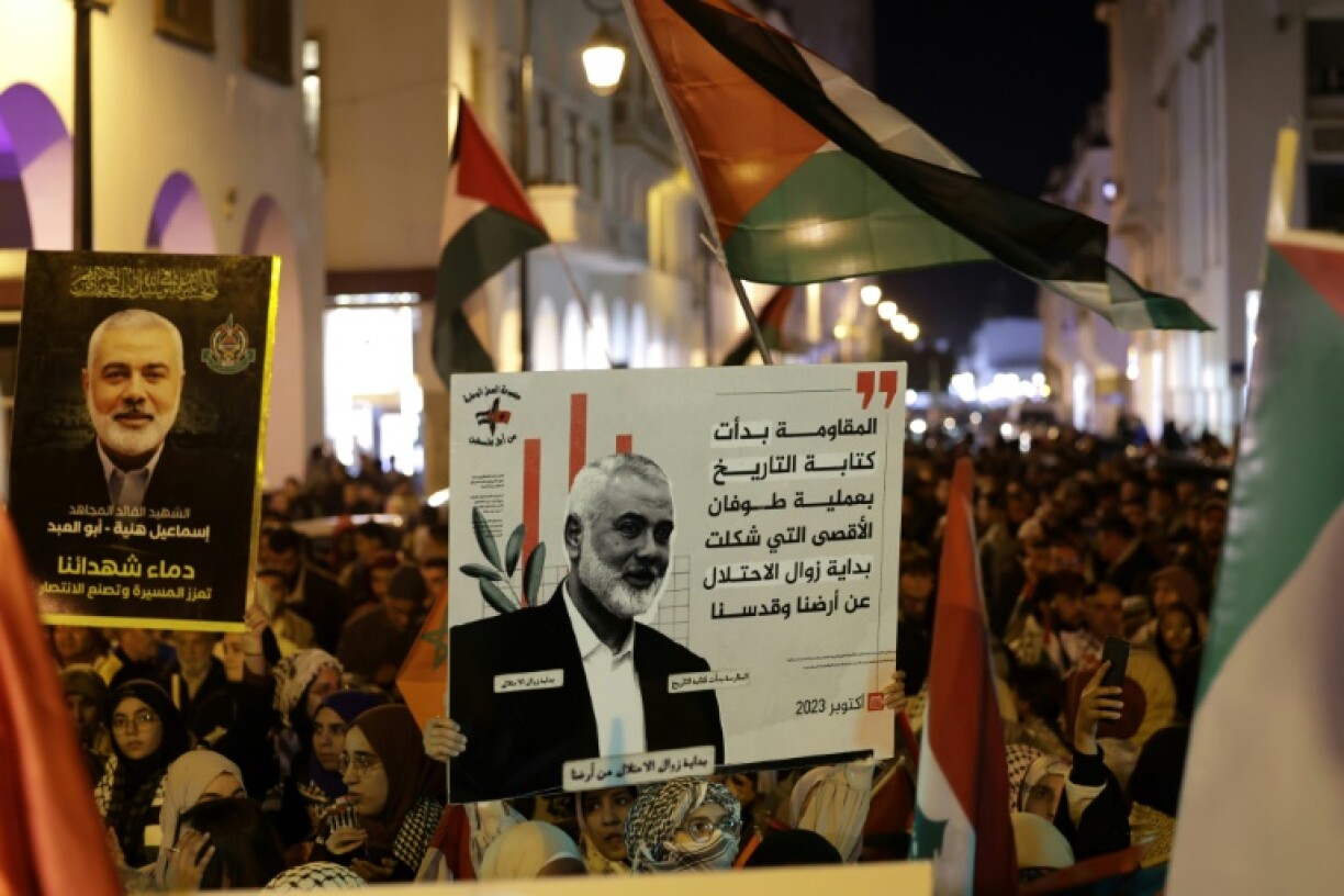 People raise placards bearing pictures of slain Palestinian Hamas political leader Ismail Haniyeh
