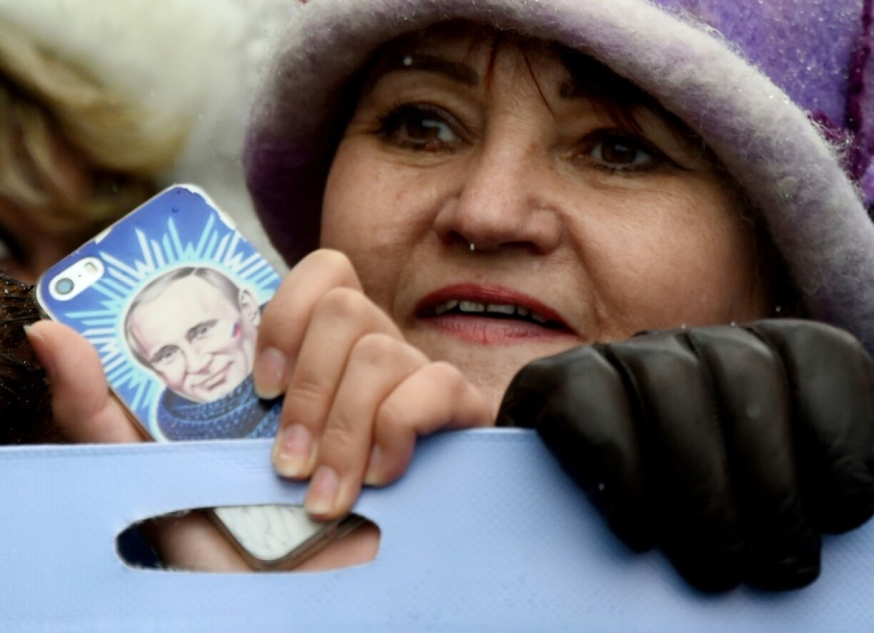 A woman holds a smartphone bearing an image of Russian President Vladimir Putin at a rally of his supporters in 2016
