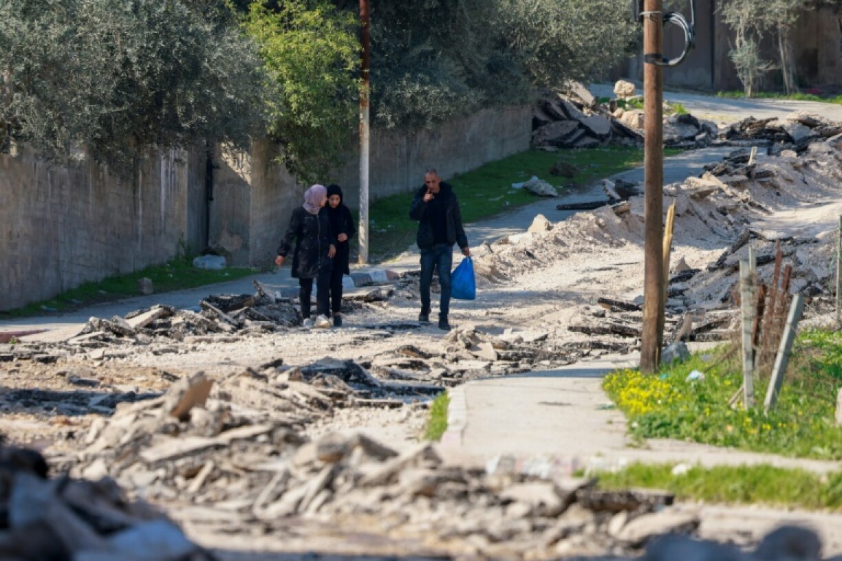 People walk along a road torn up by a bulldozer during an Israeli raid on the Jenin camp for Palestinian refugees