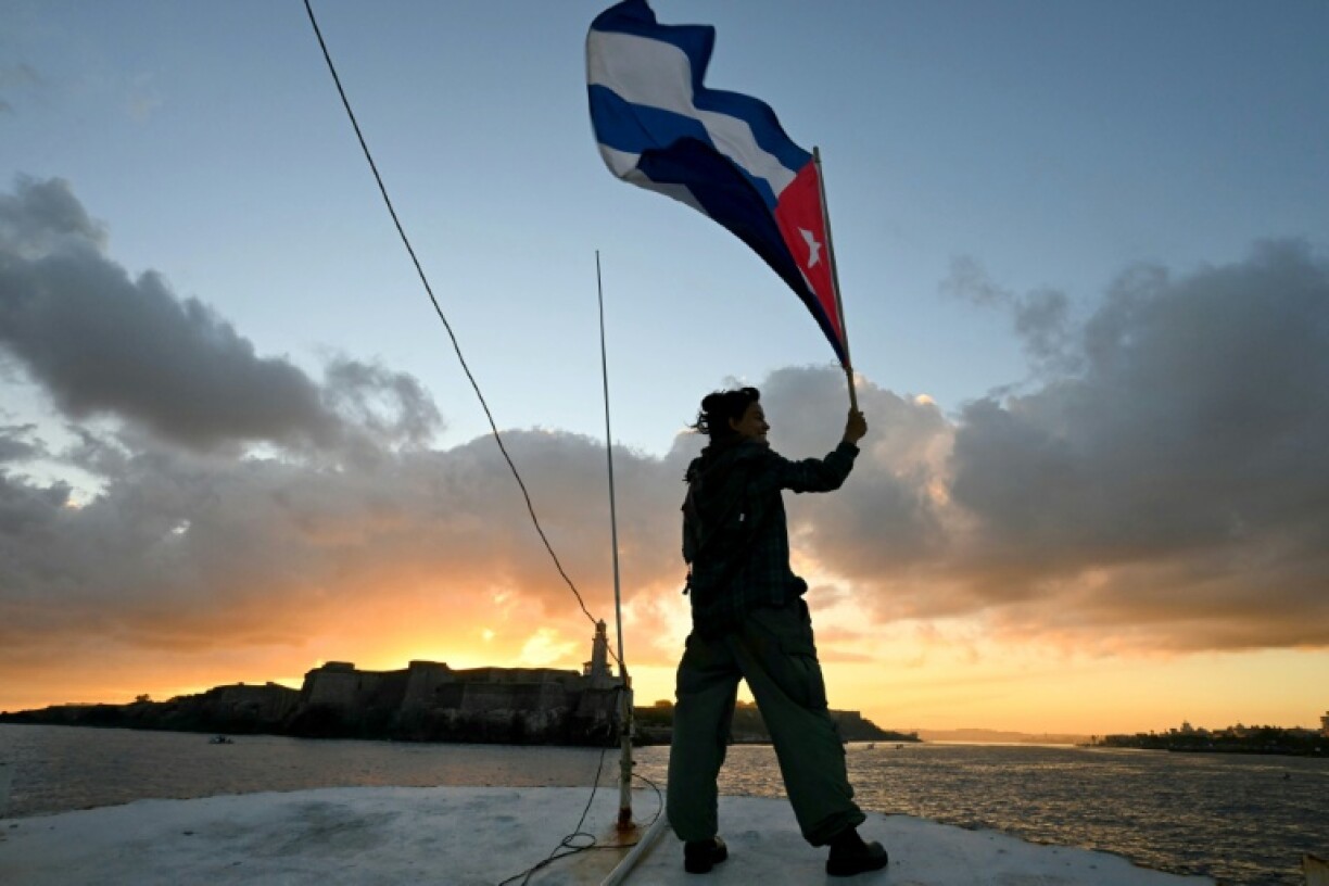 Un militant tient un drapeau cubain sur le pont du bateau de pêche Maguro, faisant partie de la flottille d'aide humanitaire, à son arrivée dans le port de La Havane, le 24 mars 2026