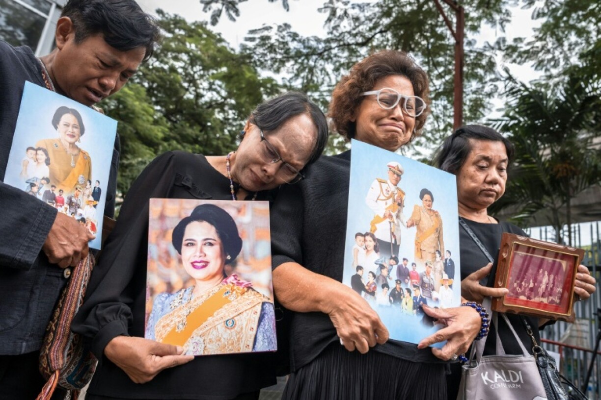 People hold portraits of Thailand's former Queen Sirikit as they gather in front of Chulalongkorn Hospital in Bangkok where she passed away late Friday