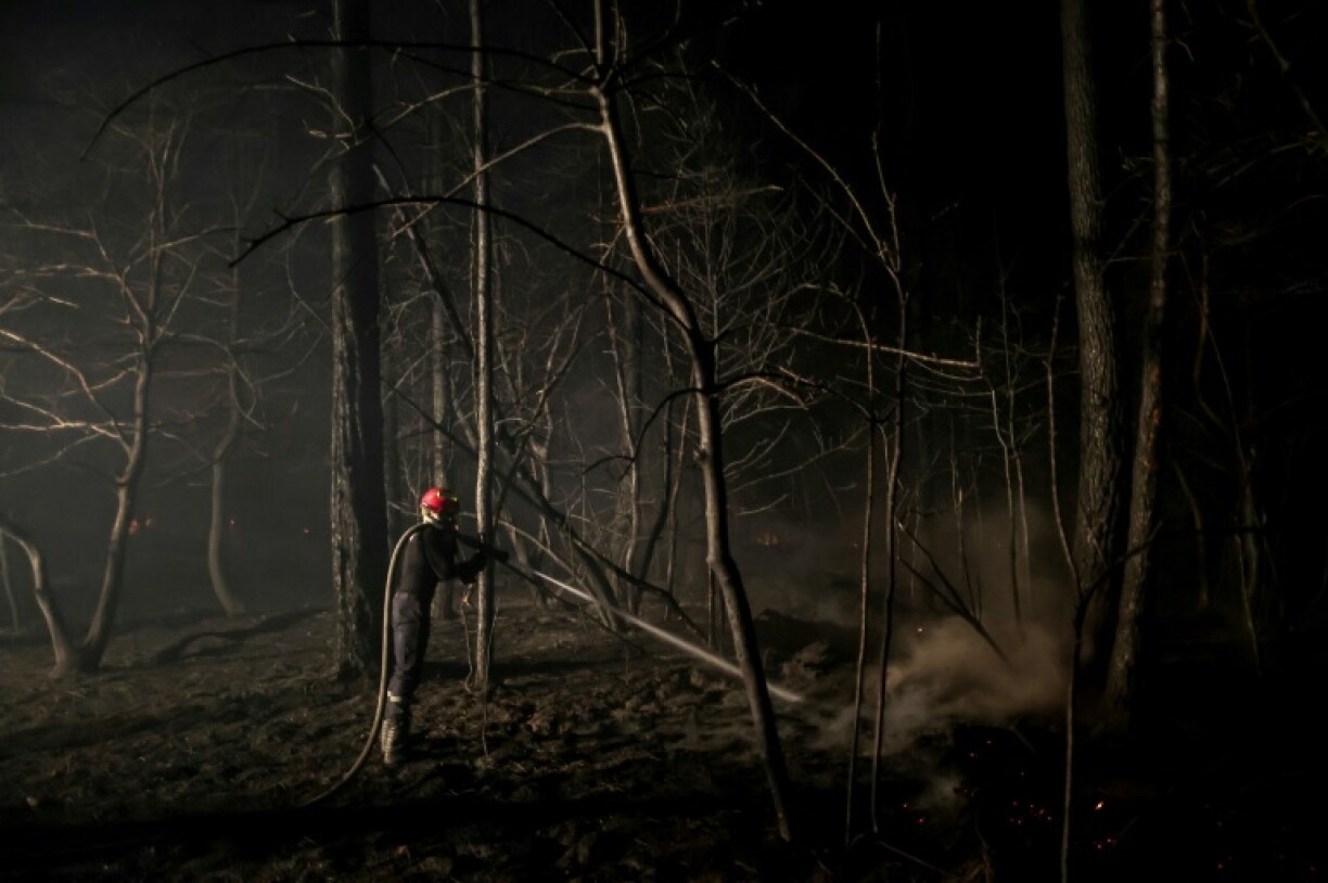Un pompier arrose une zone dévastée par le feu près de la plage du lac de Cazaux, à Teste-de Buch, en Gironde, le 15 juillet 2022