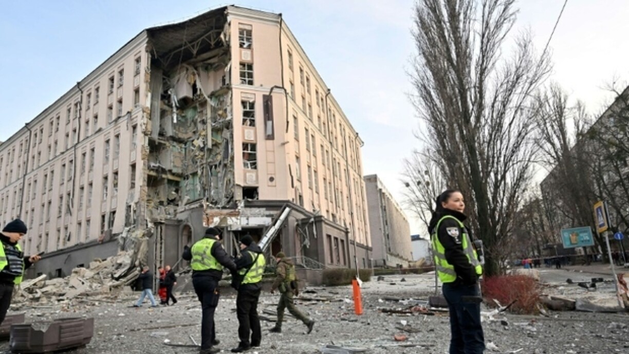 Secouristes et policiers devant un hôtel partiellement détruit à Kiev après des frappes russes sur plusieurs villes du pays, le 31 décembre 2022