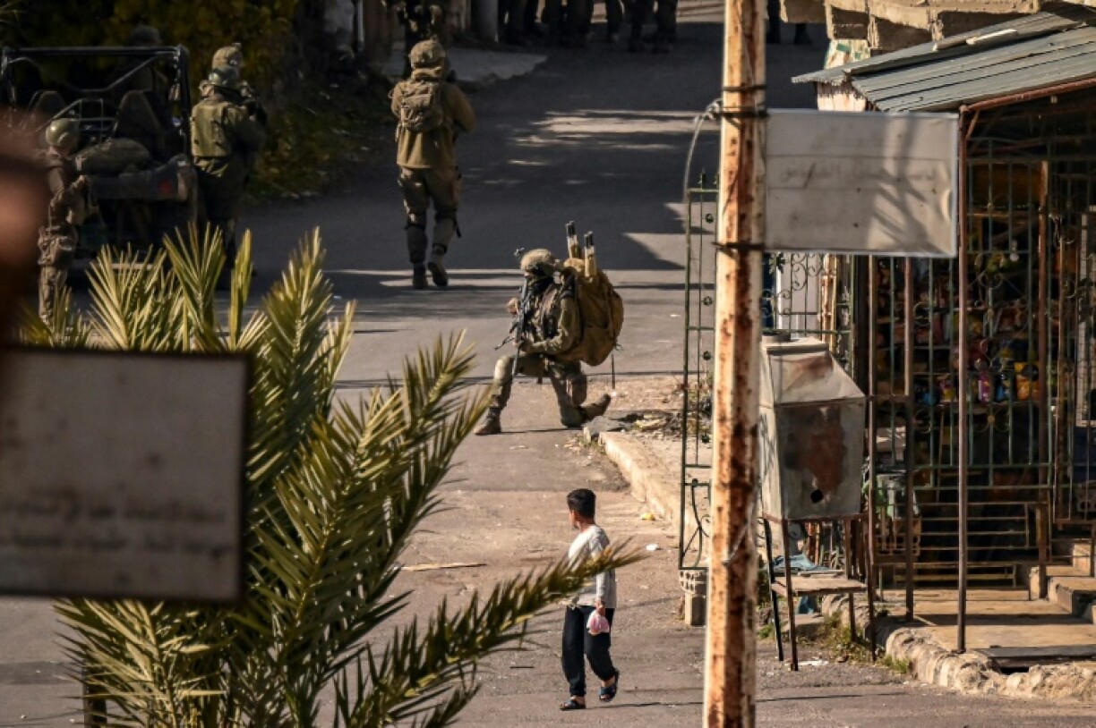 A child looks on as Israeli soldiers patrol in Jubata al-Khashab, in the UN-patrolled Golan Heights buffer zone, which Israeli troops entered after the fall of Syrian president Bashar al-Assad