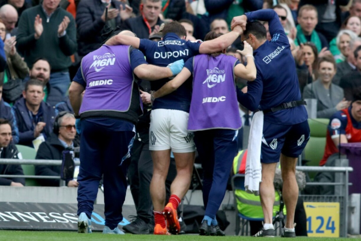 France's scrum-half Antoine Dupont (C) is helped from the field in Dublin