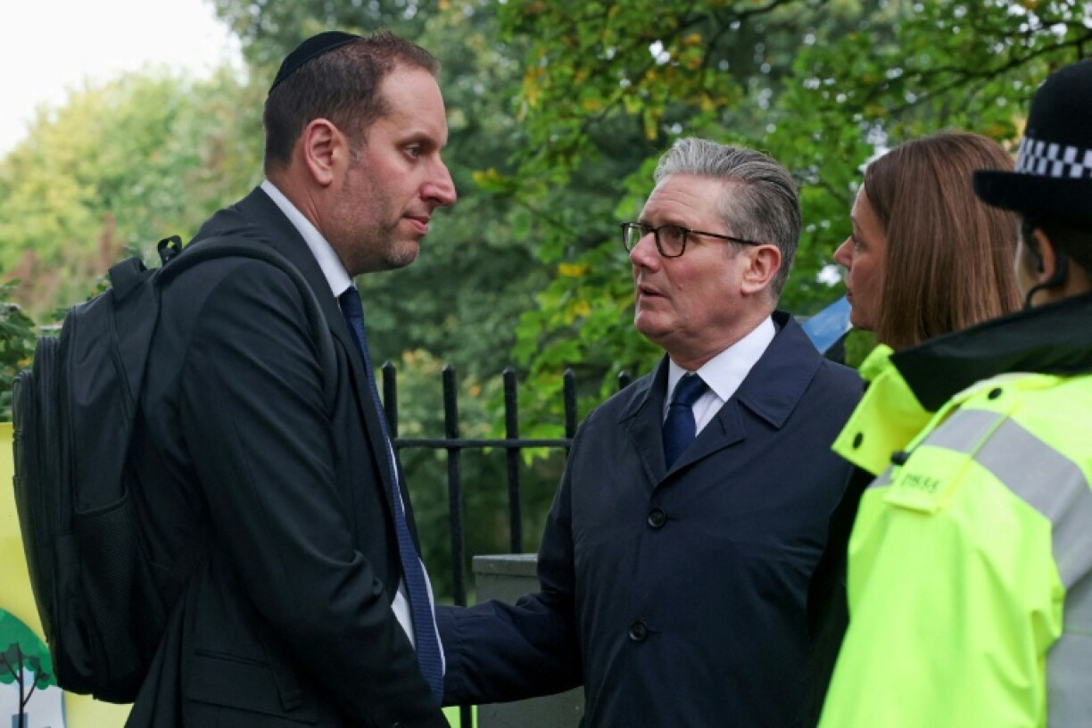 UK Prime Minister Keir Starmer (C) visits the scene of the synagogue attack